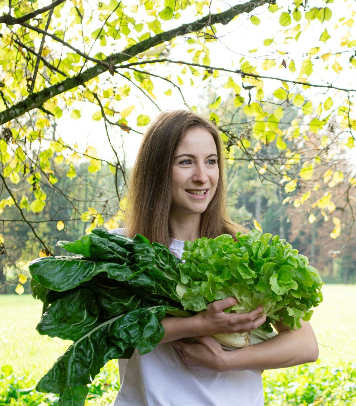 about-lisa-ernaehrungscoaching-e1670080145591 Junge Frau hält grünes Gemüse, genauer gesagt Mangold und Kopfsalat, in der Hand.